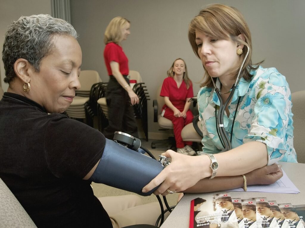 A nurse measures an older woman's blood pressure at home